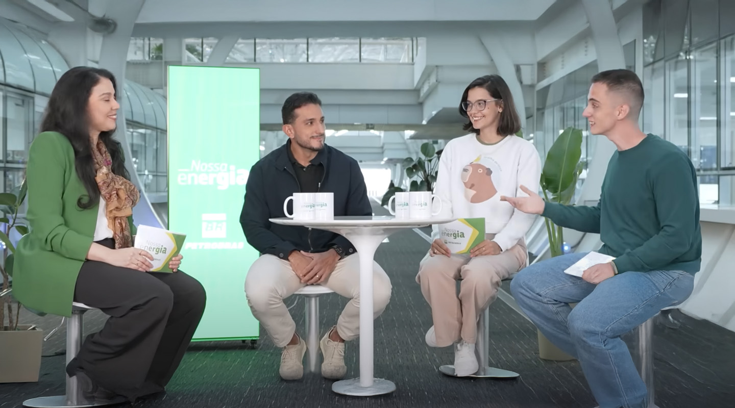 Os apresentadores Mylly e Primak conversam com o geofísico Thiago Freitas e a geóloga Érica Tavares em um estúdio com painel da Petrobras ao fundo.