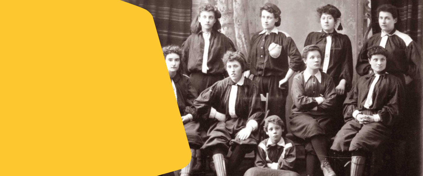 Fotografia histórica em preto e branco de um time feminino de futebol, com jogadoras posando em uniforme antigo.