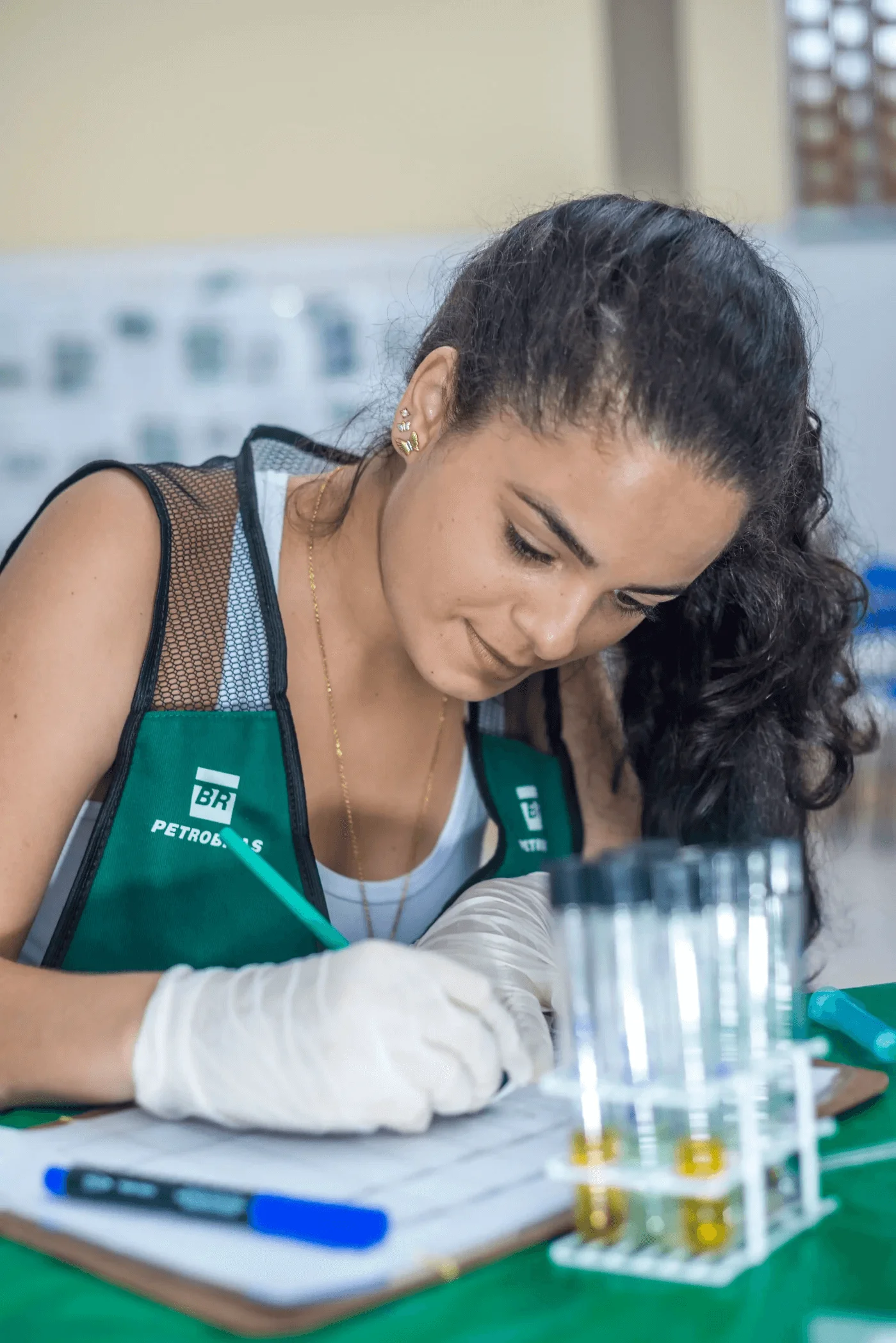 Mulher com colete da Petrobras olhando para baixo.