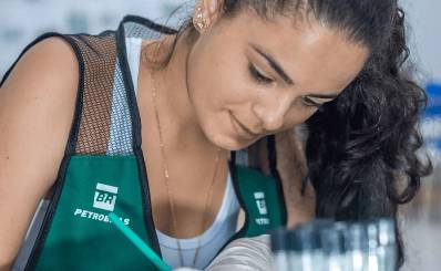 Mulher com colete da Petrobras olhando para baixo.