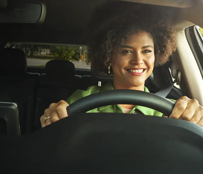 mulher dirigindo com floresta ao fundo