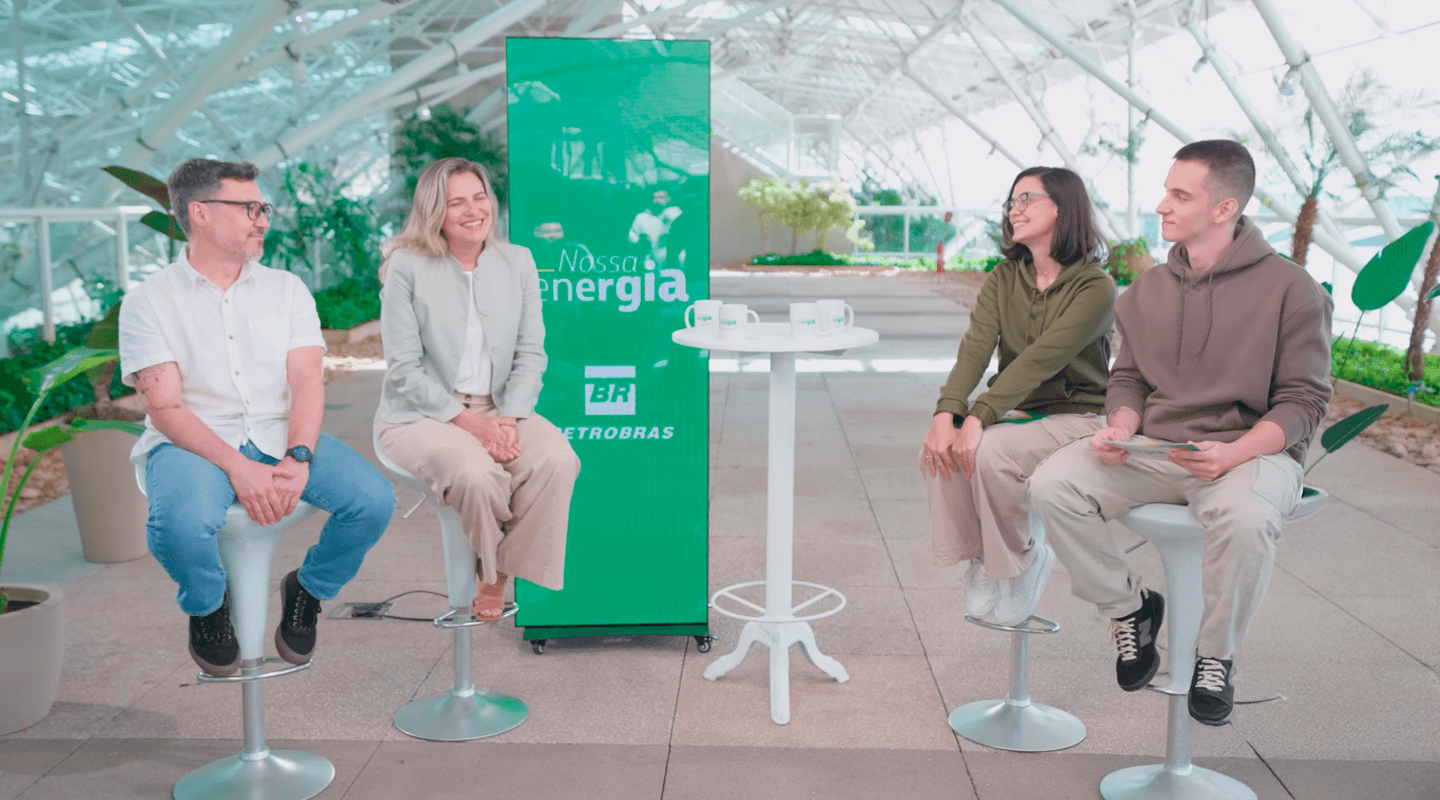 Os apresentadores Milly e Primak conversam com os biólogos Renato Fernandes e Amanda Borges, sentados em bancos altos, em um ambiente moderno e iluminado, com o banner da Petrobras ao fundo com o texto "Nossa Energia".