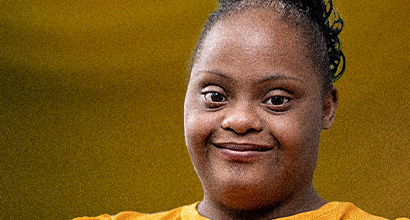 Mulher sorridente usando blusa amarela sobre fundo da mesma cor.