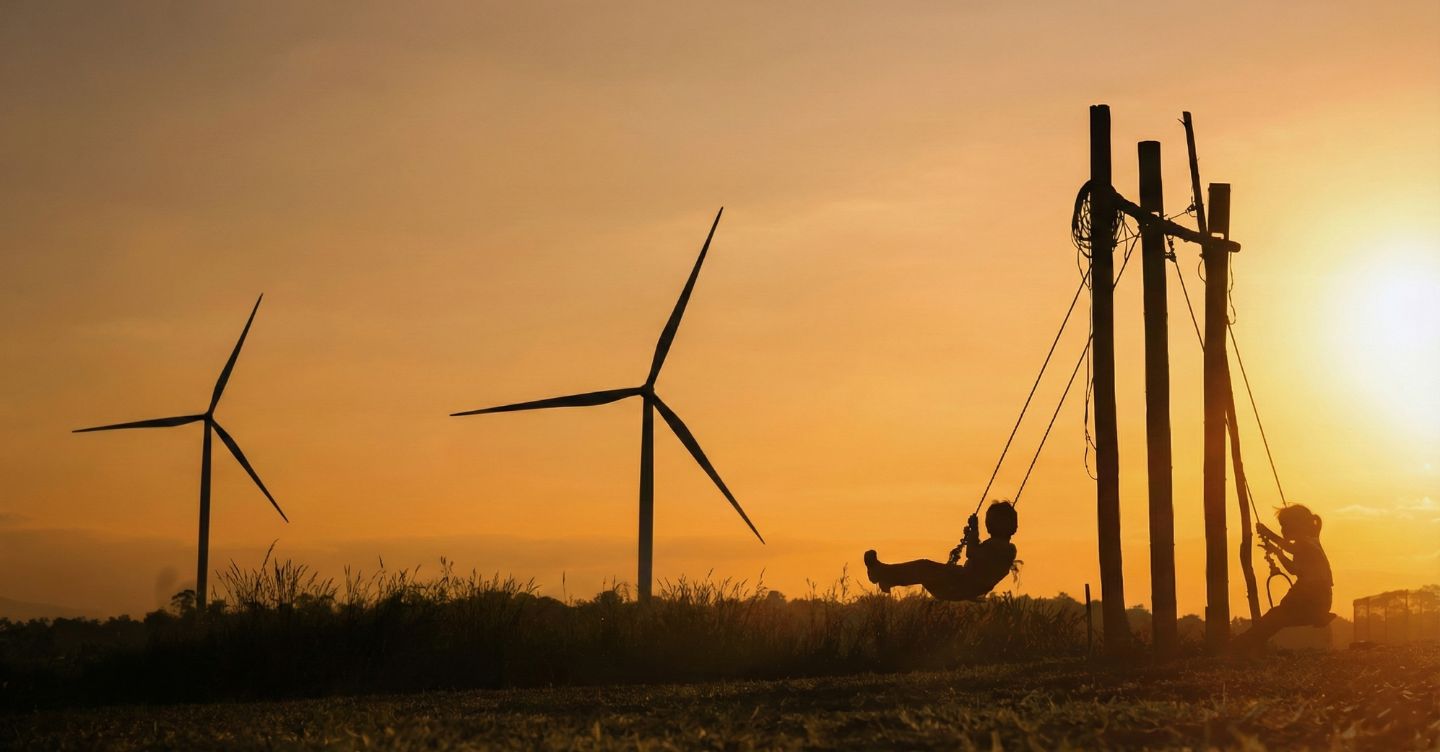 Aerogeradores no momento do pôr-do-sol com crianças no balanço