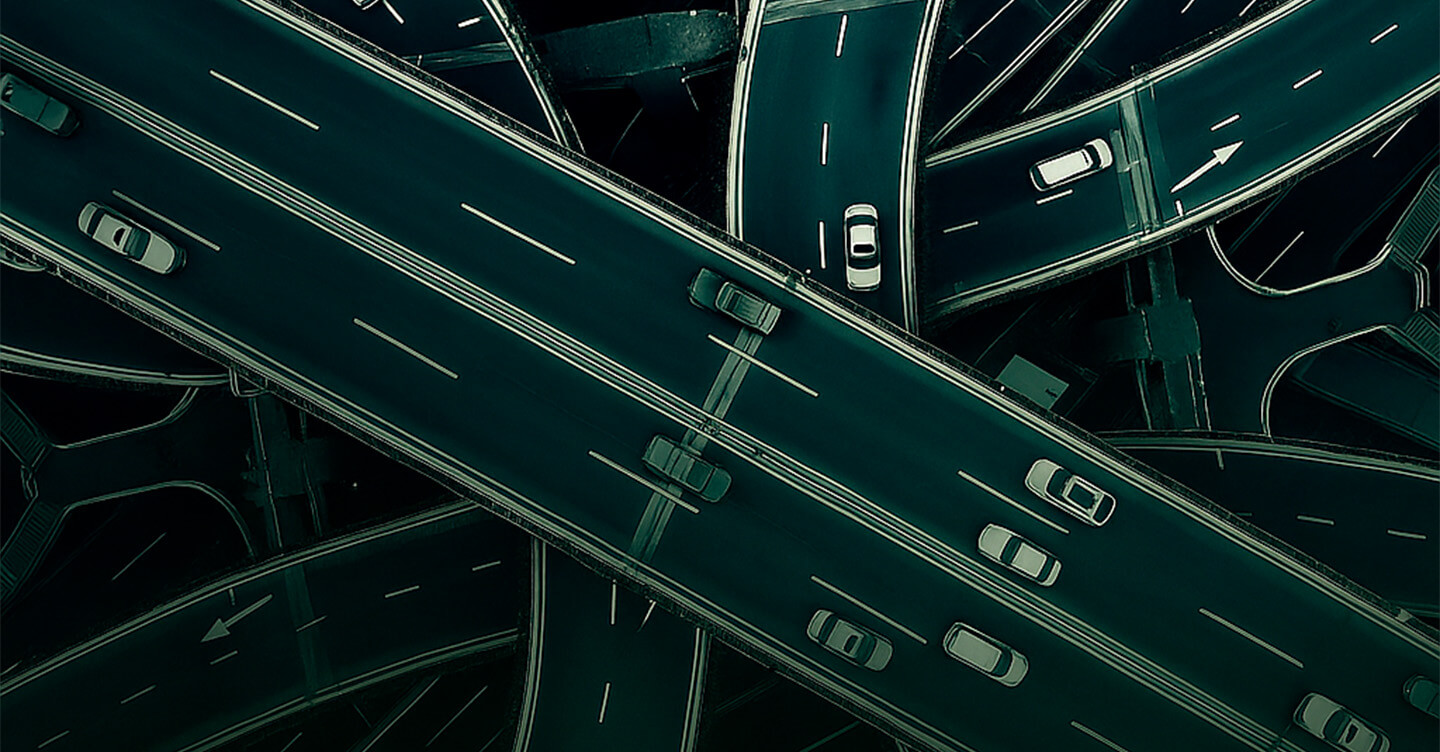 Vista aérea de um complexo de vias elevadas com carros em movimento, formando um cruzamento urbano.