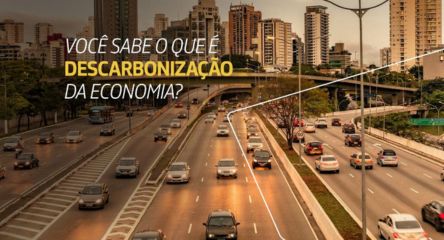 Rodovia urbana movimentada com muitos carros, prédios ao fundo e texto sobreposto: Você sabe o que é descarbonização da economia?.