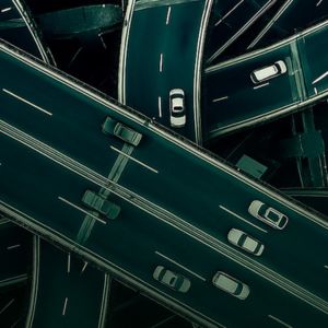 Vista aérea de um complexo de vias elevadas com carros em movimento, formando um cruzamento urbano.