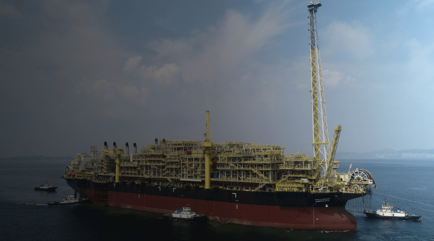 Plataforma FPSO de grande porte em operação no mar, com embarcações de apoio ao redor.