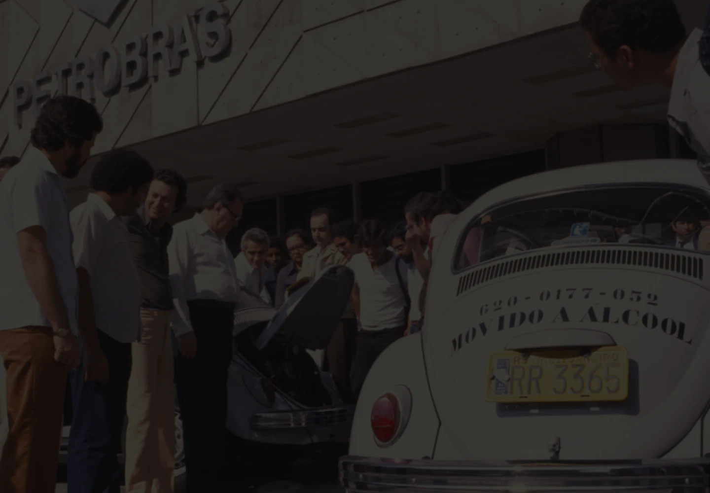 Fotografia antiga de um evento da Petrobras. Tem um fusca e várias pessoas ao arredor