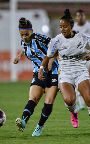 duas jogadoras de futebol disputando a bola