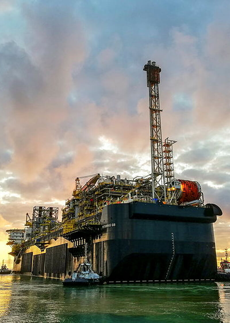 Vista frontal de plataforma FPSO em cenário de final da tarde.