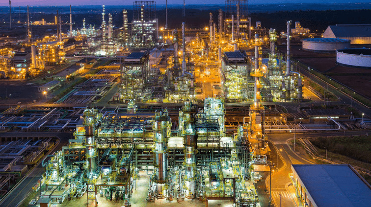 Fotografia aérea noturna da Refinaria de Paulínia, que está com sua estrutura bastante iluminada.