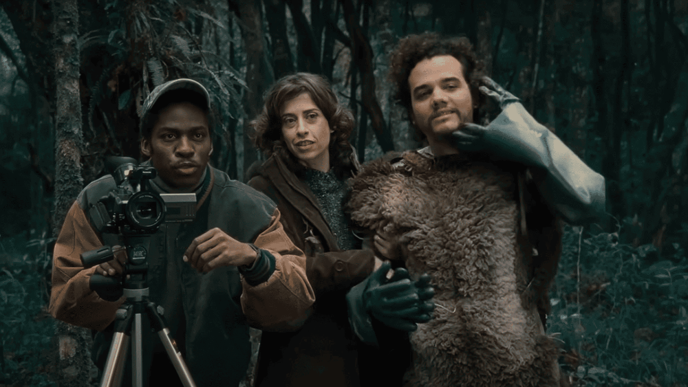 Os atores Lázaro Ramos, Fernanda Torres e Wagner Moura. Há uma câmera em um tripé em frente a Lázaro, e Wagner usa uma fantasia com pelos.