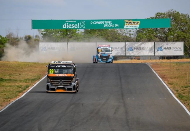 Dois caminhões de corrida da Copa Truck em uma pista, com poeira levantando atrás do primeiro veículo e uma faixa de patrocínio verde ao fundo indicando Petrobras Diesel R - O Combustível Oficial da Copa Truck.