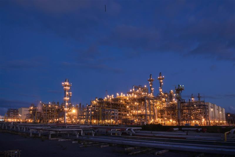 Refinaria Abreu e Lima, RNEST, à noite, iluminada, estruturas metálicas.