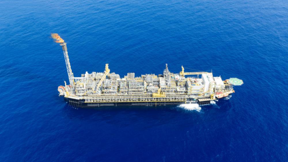 Fotografia aérea diurna da plataforma de petróleo P-77, do tipo FPSO, no oceano.